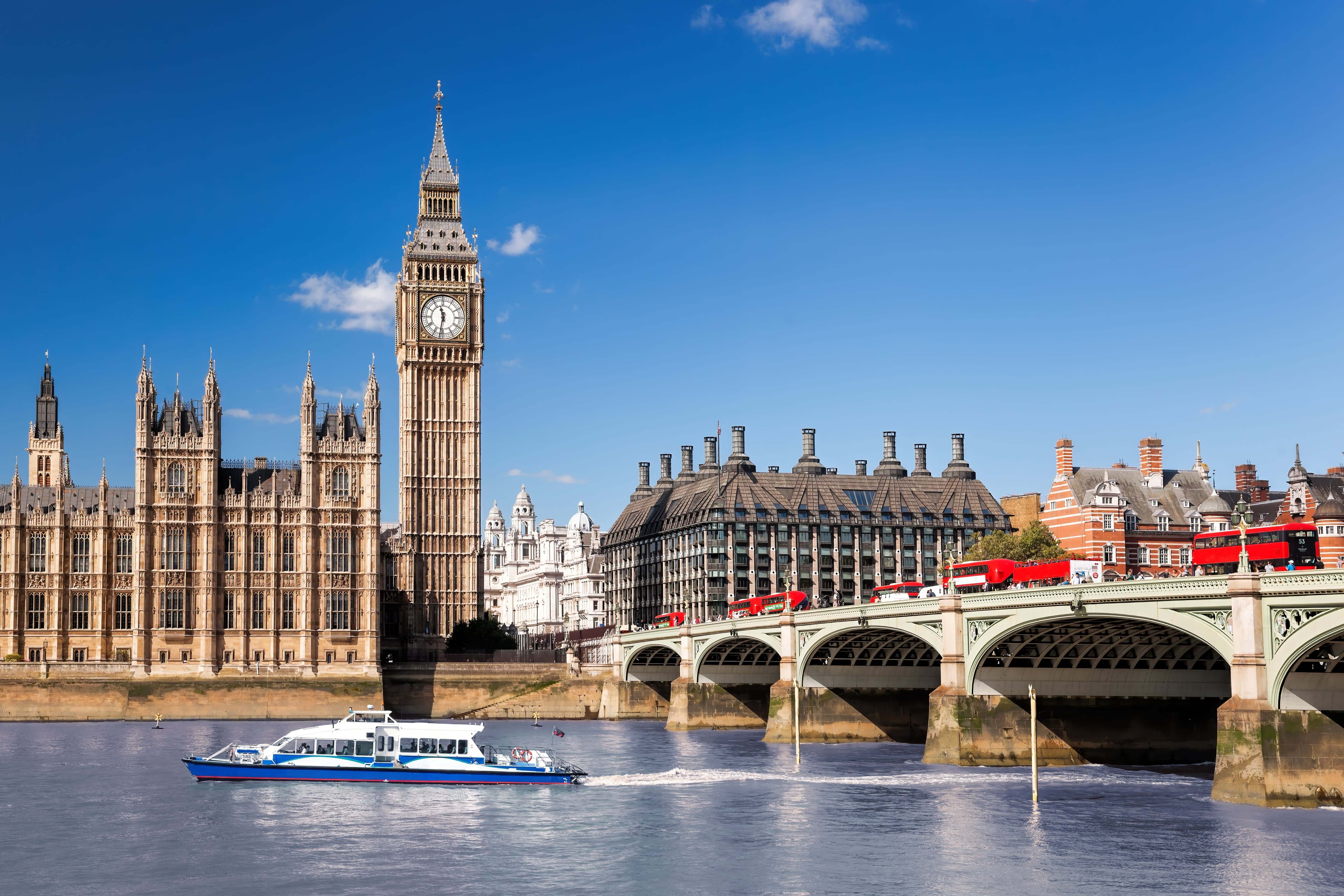 Famous Big Ben with bridge over Thames and tourboat on the river in London, England, UK